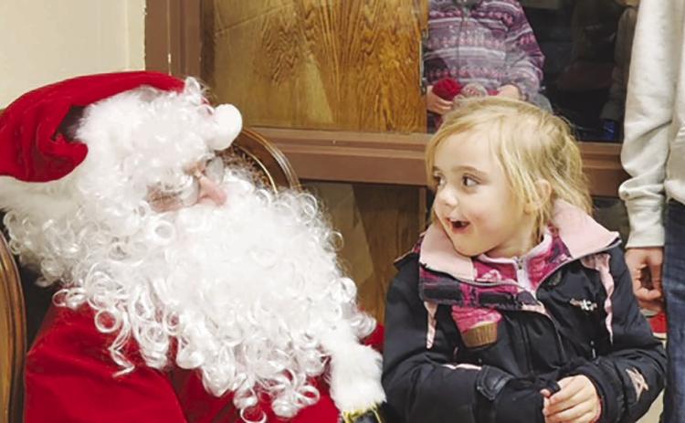 Five-year-old Lydia O’Bryan reacts with wide-eyed amazement at meeting Santa Claus during Timber Lake’s Holiday Extravaganza on Friday, Dec. 1. Lydia, daughter of Vicky Hulm and Taylor O’Bryan, said she’s been a good girl and asked Santa to bring her a stuffed cheetah. Photo by Roger Lawien