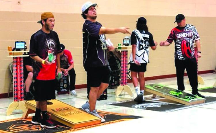 CJ Johnson, Scotty Landreaux, Bryson Andrews and Brad LeCompte compete in cornhole during a recent league night in Timber Lake. Below, James Traversie and Cadillac Ward display the Cheyenne River Cornhole League banner. Photos by Kathy Nelson