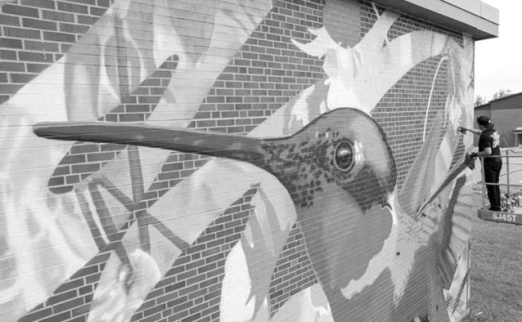 Longtime RedCan artist Cufo works on a hummingbird mural on the Si Tanka Trailer on East Landmark Avenue in Eagle Butte last week during the Cheyenne River Youth Project’s annual RedCan Graffiti Jam. It is one of eight new large-scale murals painted by the nine headlining artists at RedCan. Photo courtesy of Cheyenne River Youth Project