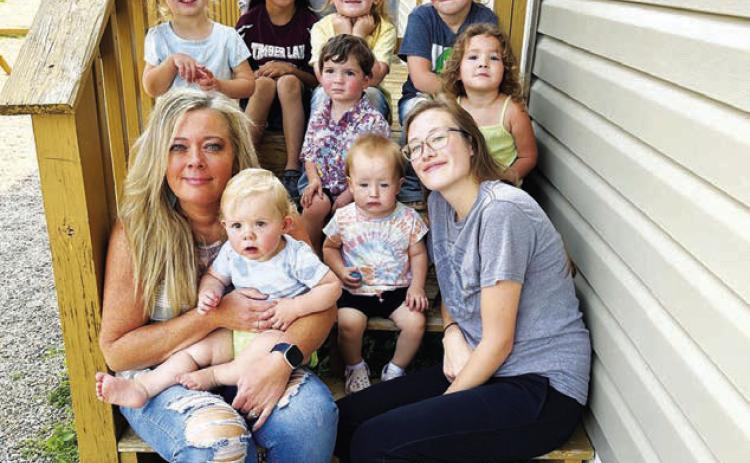 Stacy Keller (front, left) is the new interim director of Timber Lake Community Daycare. She is pictured holding Carsyn Leibel. Colty Claymore is at right with Kasen Pay Pay. In the middle row are (l-r) Marin Maher, John Booth, and Jensen Booth. In back are Kian Rousseau, Christina Rousseau, Autym Jones, and Wren Jones.