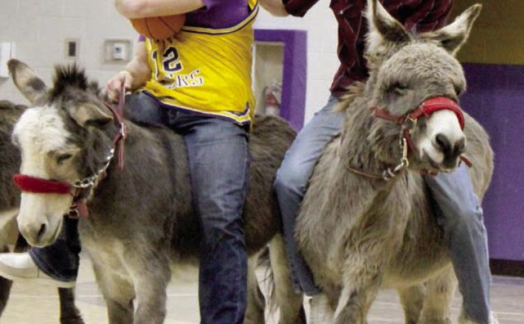 Dupree School player Roper Eaton (left) tries to protect the ball as Cruz Birkeland, playing for the Farmers &amp; Ranchers team, attempts to steal it while staying atop his donkey during Donkey Basketball sponsored by the Dupree Booster Club last Thursday, Jan 23. Photo by Patty Peacock