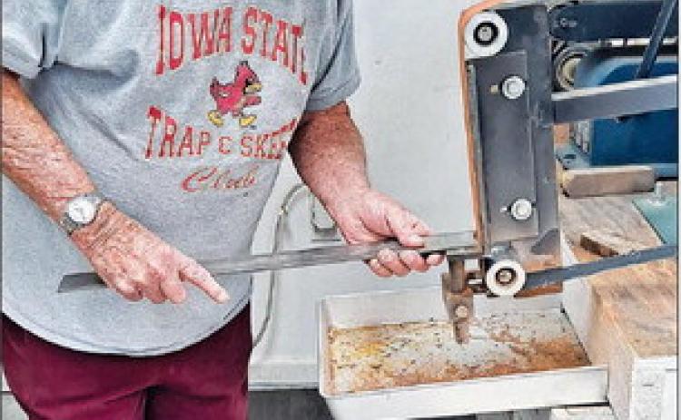 Wearing his protective mask, Jack uses the grinder on a piece of steel.