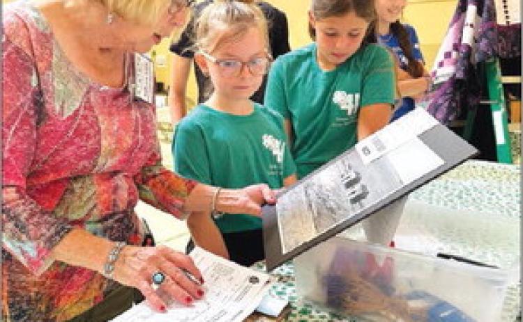 Judge Adele Enright looks at photography entries with Stella Nilson and Finley Boldt at the Dewey County 4-H Achievement Day on July 27.