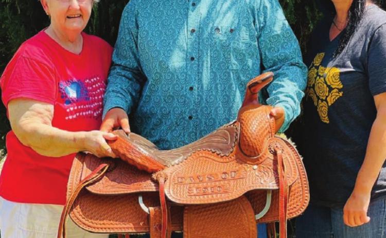 Carol Dellis (LEFT) with her daughter Sarah and 15-year-old grandson, Garrett, with the Days of 1910 saddle that Carol and her husband, Billy Bob Dellis, built in 1983. “It’s our legacy,” Carol said. “When it came I just hugged it. Just sitting here looking at it gives me such peace.”
