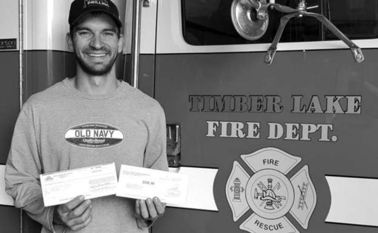 Scott Biegler of the Timber Lake Volunteer Fire Dept. accepts a $500 donation from Moreau-Grand Electric and Basin Electric.