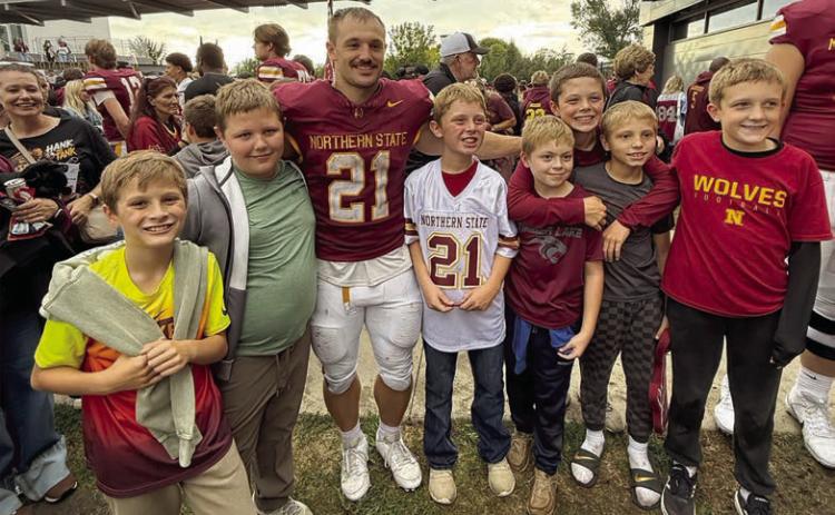 Vern Long (in white jersey) celebrated his tenth birthday at a packed-house Gypsy Days game at NSU in Aberdeen on September 26. The highlight of the day for Vern and his friends was getting to see Hank Kraft (in maroon jersey) after the game and have his #21 jersey autographed. “Hank the Tank” made two touchdowns as the NSU Wolves defeated University of Mary 24-17. L-R are Jackson Quaschnick, Hank Anderson, Vern Long, Ryder Spiel, Landon McComsey, Barrett Hermes, and Oliver McComsey.