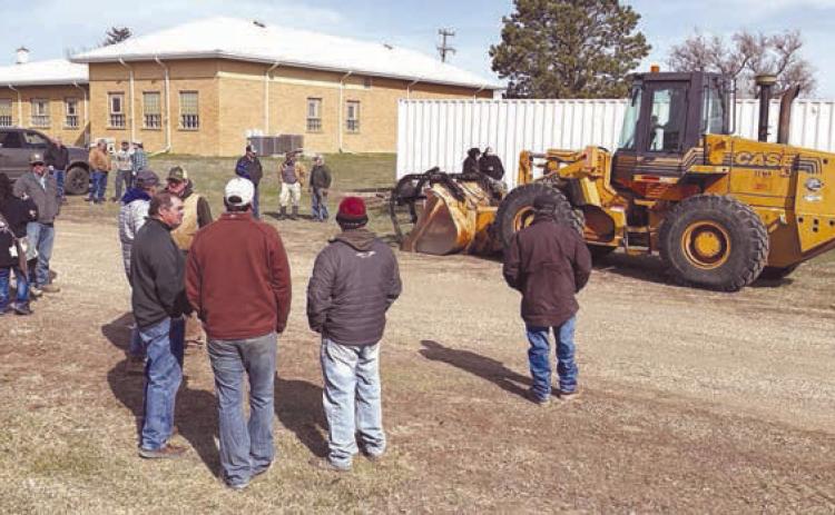 Bidders and onlookers lined up for auction of the surplus 1997 Case loader from the Dewey County Highway Department on April 8. Rod Enright conducted the auction, which brought $59,000 from Dan Molitor of Morristown. Photo by Kathy Nelson