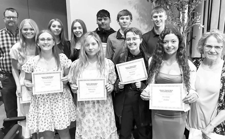 Western Dakota Bank awarded $1000 scholarships to 12 students. The 10 from Timber Lake are pictured with Rusty Gebhardt (back, left) and Karma Nash (front, right) of Western Dakota Bank. They are (Front (l-r) Emma Johnston, Maddie Lou Gray, Maria Scherer, Arianna Bieber; Back: Hailey Roggow, Gailup Bollinger, Geana Bollinger, Hayden Thompson, Gavin White, and Holden Gill. The other two recipients are Fallon Peterson of Faith and Katelyn Gebhart of Lemmon.