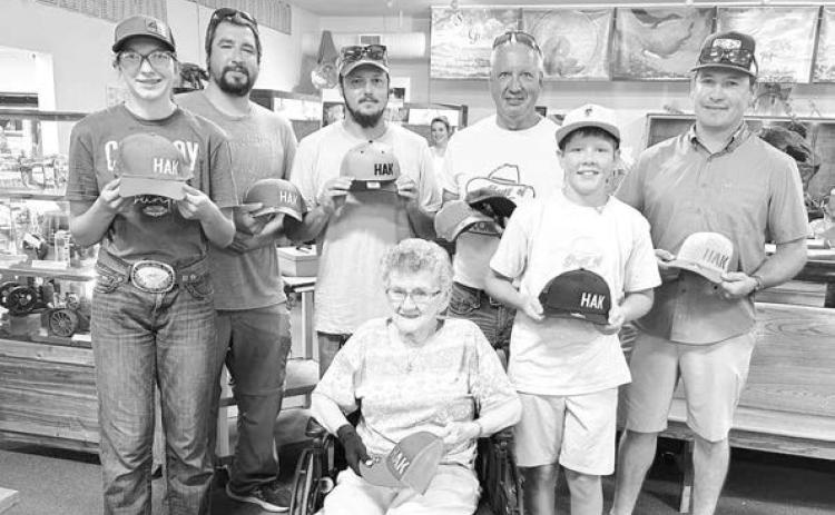 Pictured with Joyce Kraft and the HAK caps they all bought for chances to win a Herman Kraft knife are (l-r) Bricelyn Pederson of Broken Heart Ranch, Josh Biegler (who won the knife), Dalton Bender, David Biegler, Monroe Kraft (Tyrone), and Duffy Dupris.