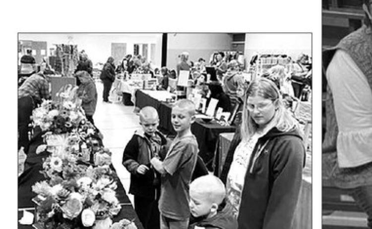 Twenty-seven vendors, some with two tables of wares, drew browsers at shoppers at the annual Fall Craft Fair at Timber Lake on November 5. Here Megan Zeug and sons (L-R) Eli, Isaac and Andrew admire wooden flowers.
